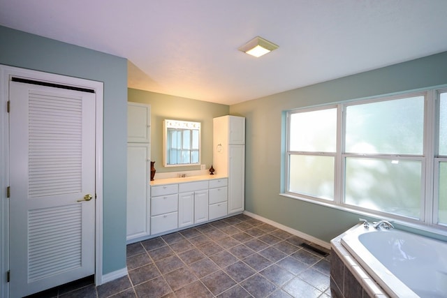 bathroom featuring vanity, a relaxing tiled tub, tile patterned floors, and a wealth of natural light