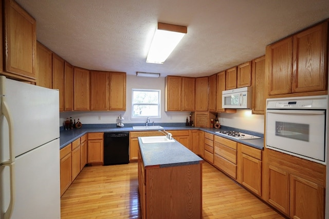 kitchen featuring light hardwood / wood-style floors, a textured ceiling, a center island, and white appliances