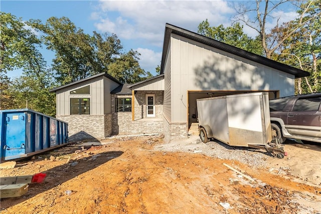 view of side of property with a garage, board and batten siding, and brick siding