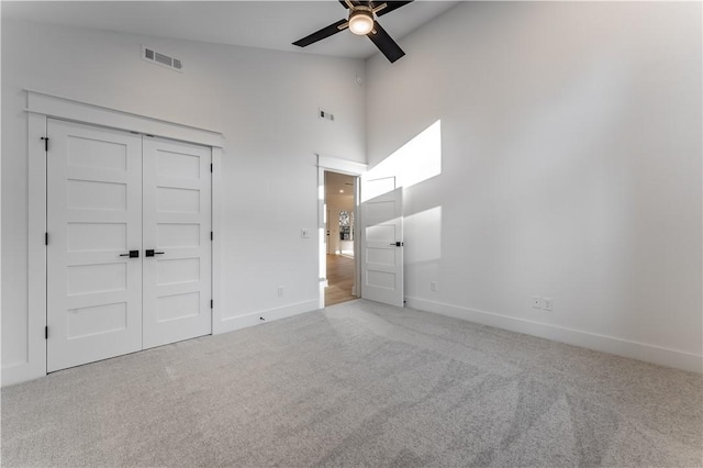 unfurnished bedroom featuring high vaulted ceiling, carpet, visible vents, and baseboards