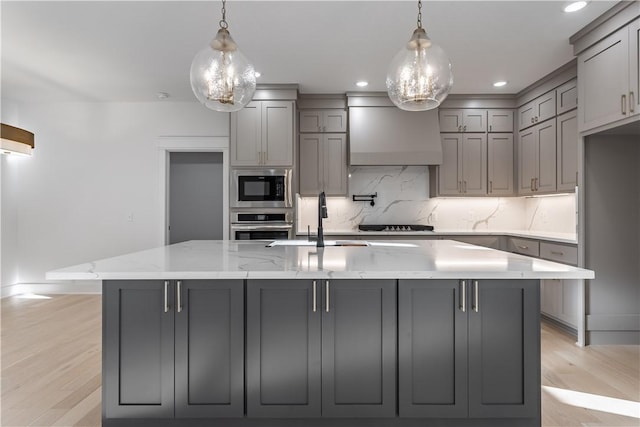 kitchen with light stone counters, a sink, stainless steel oven, built in microwave, and wall chimney exhaust hood