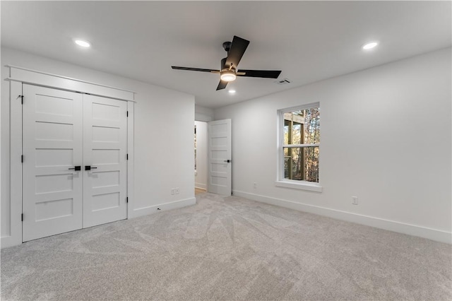 unfurnished bedroom featuring ceiling fan, light colored carpet, and a closet