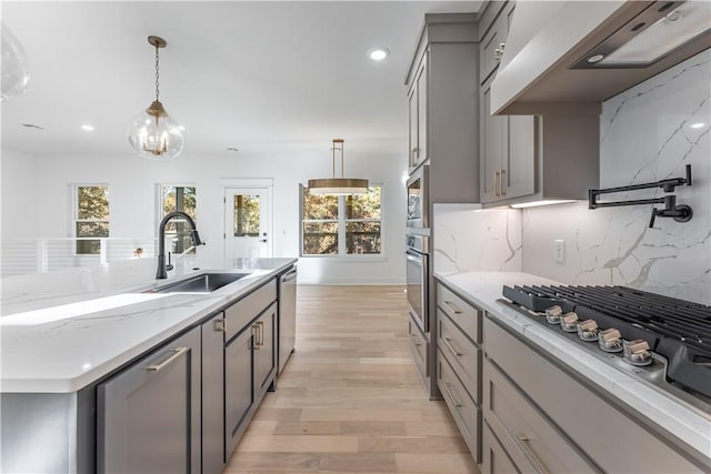 kitchen featuring pendant lighting, stainless steel appliances, custom range hood, gray cabinetry, and a sink