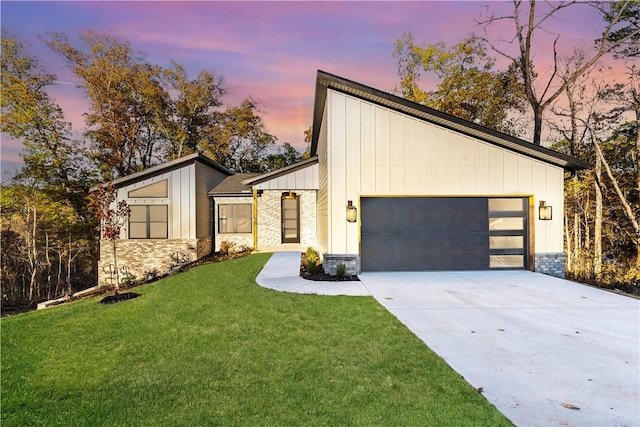 view of front of house with a lawn, board and batten siding, a garage, stone siding, and driveway