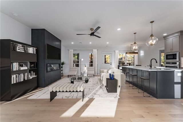 living area featuring a ceiling fan, a wealth of natural light, light wood finished floors, and recessed lighting