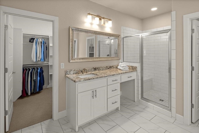 bathroom featuring a shower with door and vanity