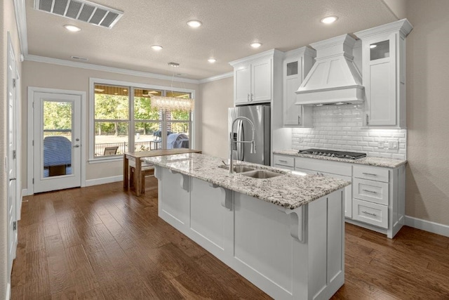 kitchen featuring white cabinets, custom range hood, dark wood-type flooring, black gas stovetop, and a center island with sink