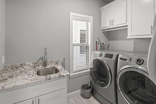 laundry area with light tile patterned floors, cabinets, sink, and washing machine and clothes dryer