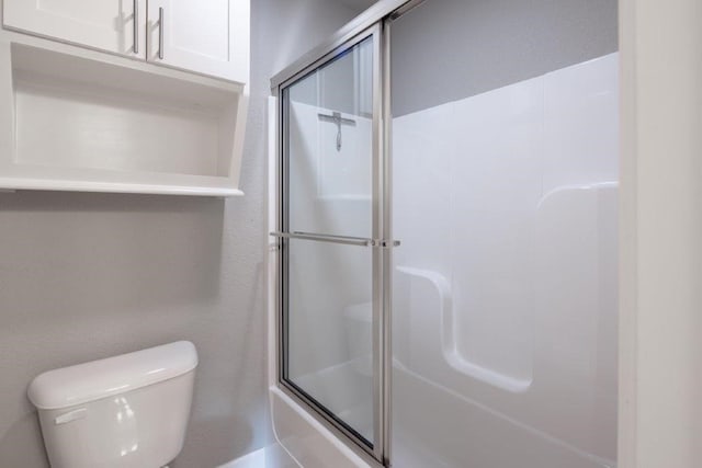 bathroom featuring enclosed tub / shower combo and toilet