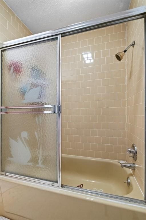 bathroom featuring shower / bath combination with glass door and a textured ceiling