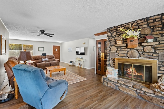 living room featuring a textured ceiling, a fireplace, ceiling fan, and dark wood-type flooring