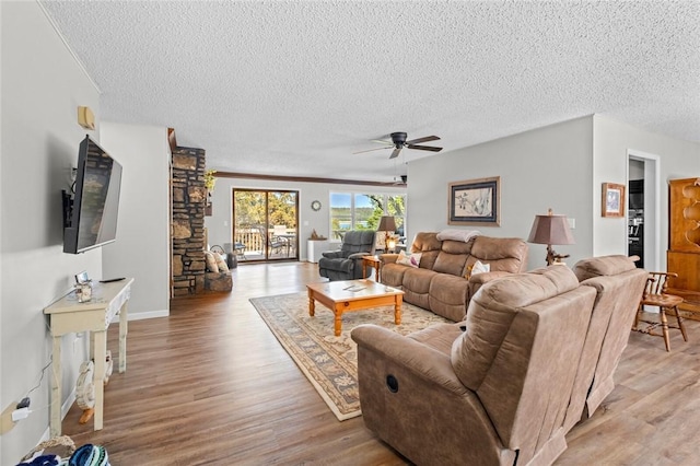 living room featuring ceiling fan, a textured ceiling, and light wood-type flooring