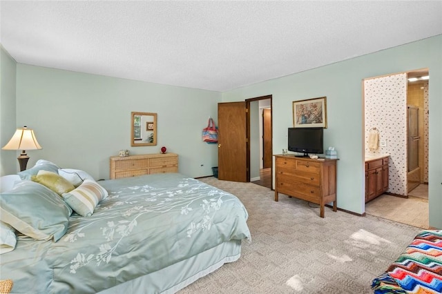 carpeted bedroom featuring a textured ceiling and ensuite bath