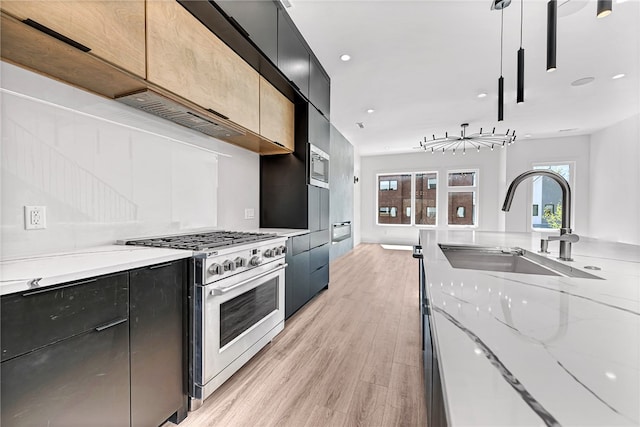 kitchen featuring light stone counters, sink, light hardwood / wood-style floors, appliances with stainless steel finishes, and decorative light fixtures