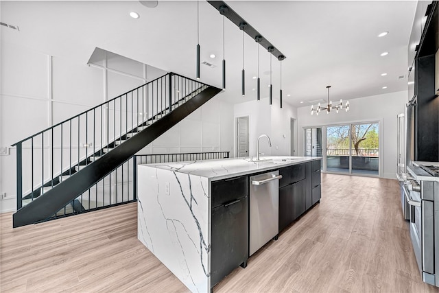 kitchen featuring pendant lighting, sink, a large island, an inviting chandelier, and light hardwood / wood-style floors