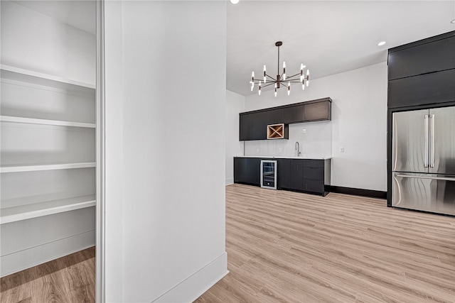 kitchen featuring an inviting chandelier, beverage cooler, light hardwood / wood-style flooring, high end refrigerator, and sink