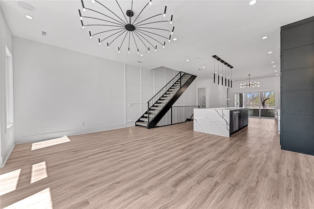 unfurnished living room with a notable chandelier, sink, and light hardwood / wood-style floors