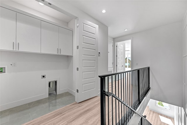 laundry room featuring electric dryer hookup, light wood-type flooring, hookup for a washing machine, and cabinets