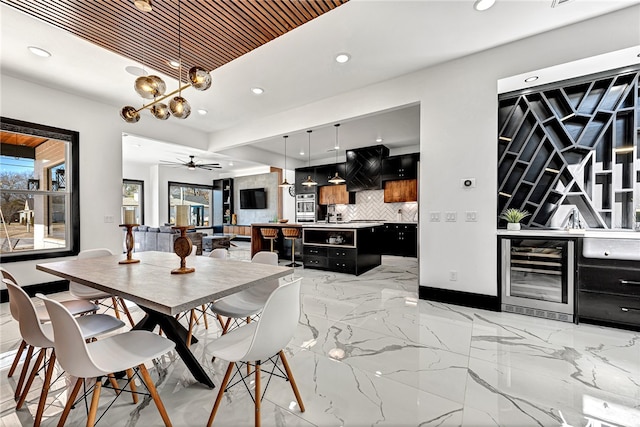 dining area featuring ceiling fan with notable chandelier and wine cooler