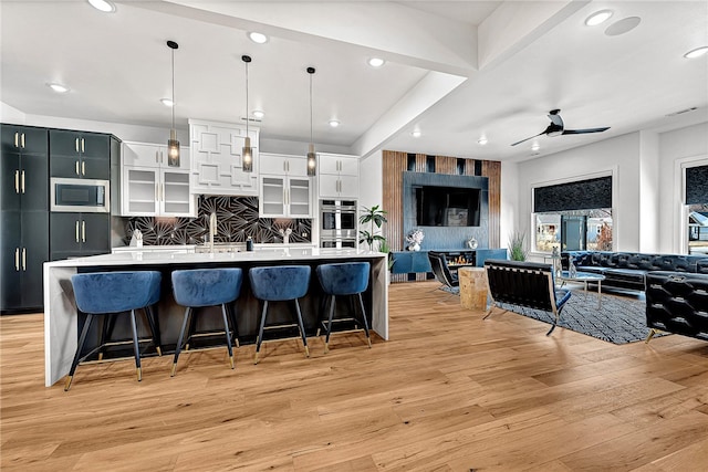 kitchen featuring hanging light fixtures, tasteful backsplash, light hardwood / wood-style flooring, appliances with stainless steel finishes, and a spacious island