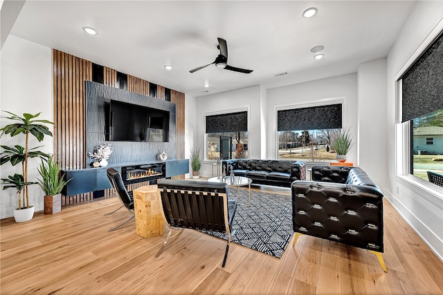 living room with a healthy amount of sunlight, ceiling fan, and light hardwood / wood-style flooring