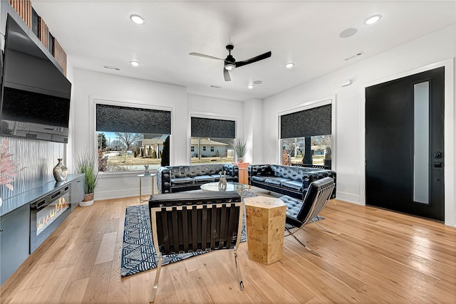 living room featuring ceiling fan, light wood-type flooring, and a healthy amount of sunlight