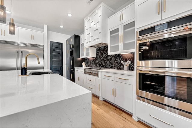 kitchen with sink, appliances with stainless steel finishes, light hardwood / wood-style flooring, and white cabinetry