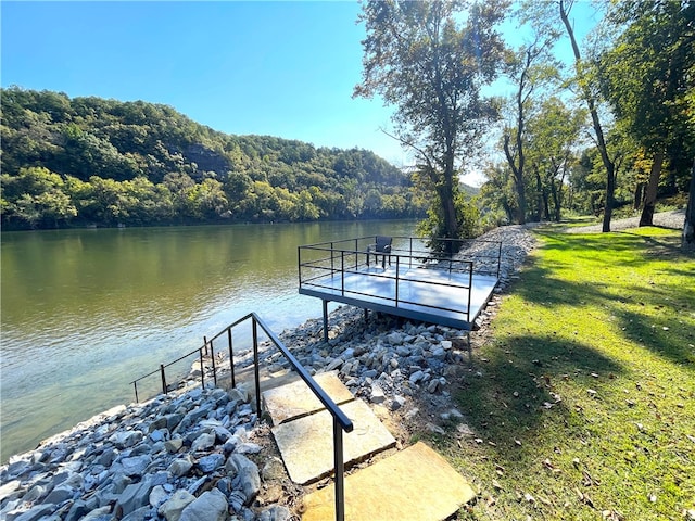 view of dock with a water view and a yard