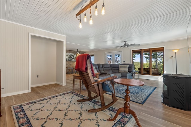 living room with a wood stove, hardwood / wood-style flooring, ceiling fan, and ornamental molding