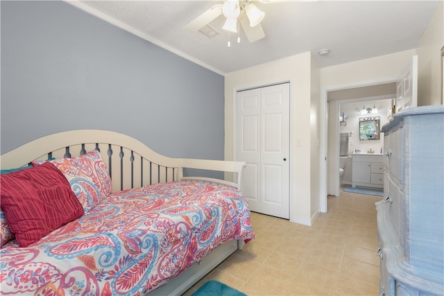 tiled bedroom featuring ensuite bathroom, ceiling fan, and a closet