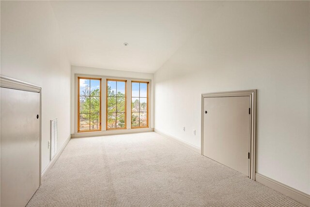 empty room with high vaulted ceiling and light carpet