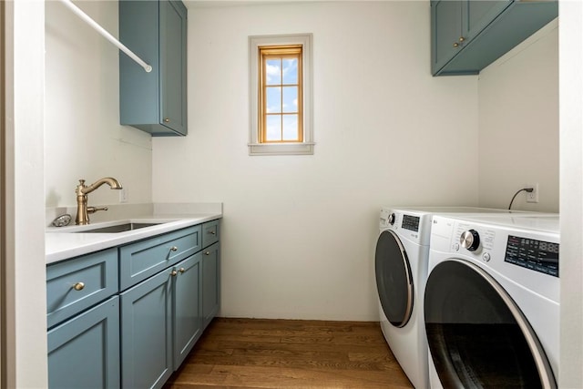 clothes washing area featuring cabinets, washer and clothes dryer, dark hardwood / wood-style floors, and sink