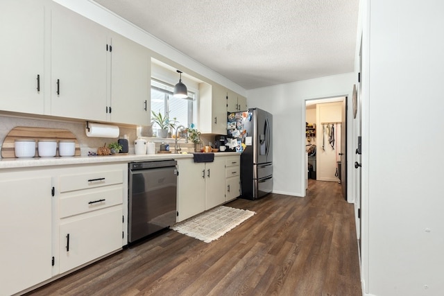 kitchen featuring a textured ceiling, appliances with stainless steel finishes, dark wood-type flooring, and white cabinetry