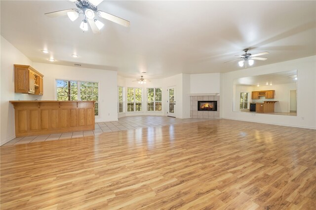 unfurnished living room featuring light hardwood / wood-style floors and a tiled fireplace