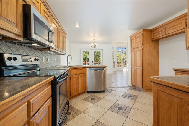 kitchen featuring appliances with stainless steel finishes, french doors, tasteful backsplash, sink, and light tile patterned floors