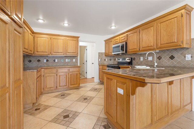 kitchen featuring a breakfast bar, sink, light tile patterned flooring, kitchen peninsula, and stainless steel appliances