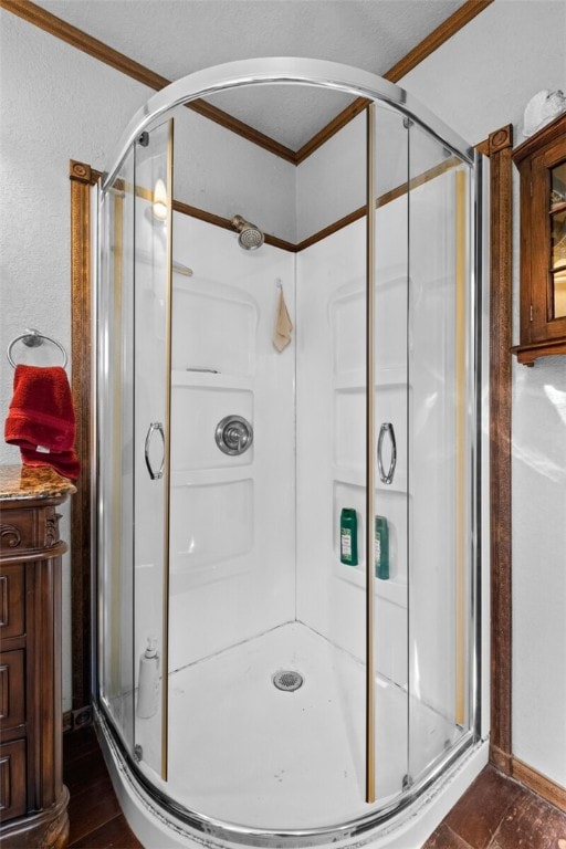 bathroom featuring ornamental molding, hardwood / wood-style flooring, and a shower with shower door