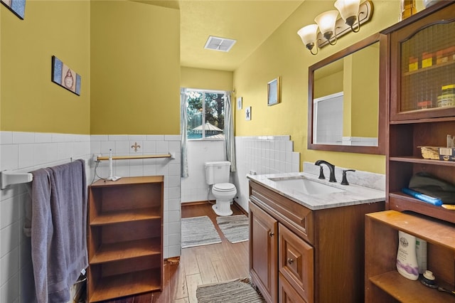 bathroom featuring vanity, hardwood / wood-style flooring, tile walls, and toilet