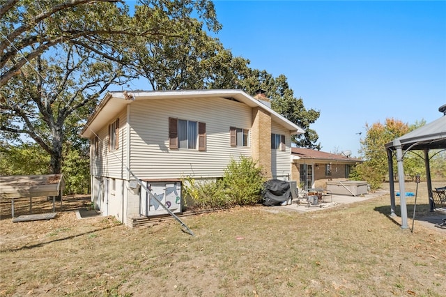 rear view of property with a gazebo, a yard, a patio, and a hot tub