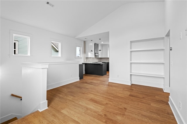 unfurnished living room with light hardwood / wood-style floors and high vaulted ceiling