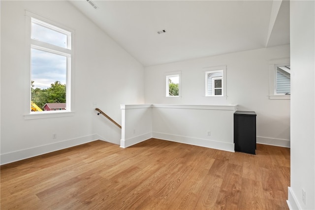 unfurnished room with light wood-type flooring and vaulted ceiling