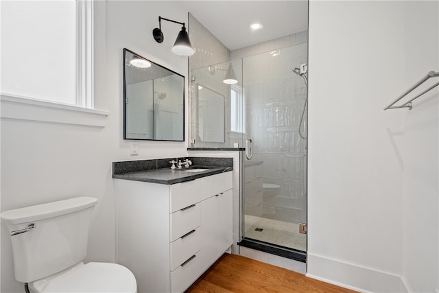 bathroom with a shower with shower door, hardwood / wood-style flooring, vanity, and toilet