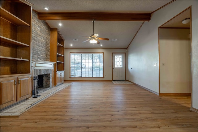 unfurnished living room featuring lofted ceiling with beams, light wood-type flooring, ceiling fan, a fireplace, and a textured ceiling