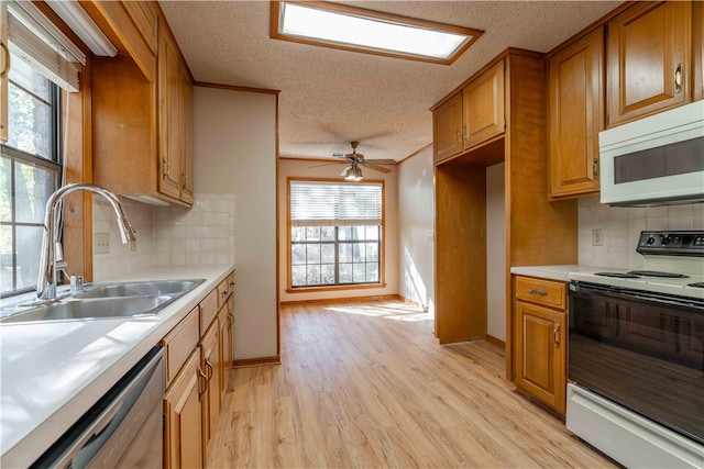 kitchen with light wood-type flooring, backsplash, white appliances, and a wealth of natural light