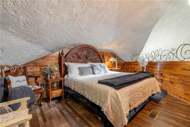 bedroom featuring dark wood-type flooring, a textured ceiling, lofted ceiling, and wooden walls