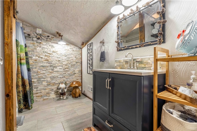 bathroom featuring vanity, lofted ceiling, and a textured ceiling