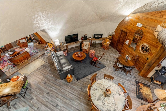 unfurnished living room featuring a textured ceiling, lofted ceiling, wooden walls, and wood-type flooring