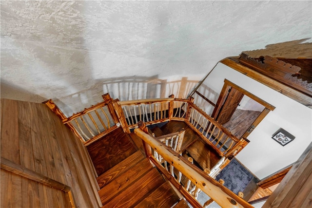 staircase with hardwood / wood-style floors and a textured ceiling