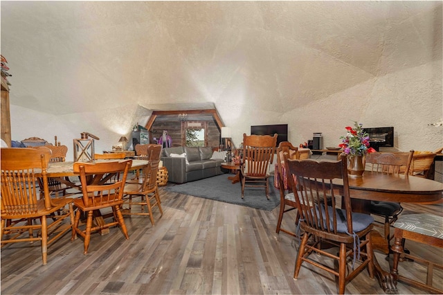 dining room with hardwood / wood-style floors, lofted ceiling, and a textured ceiling