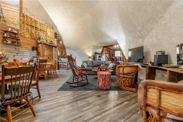 interior space featuring wood walls, hardwood / wood-style floors, lofted ceiling, and a textured ceiling